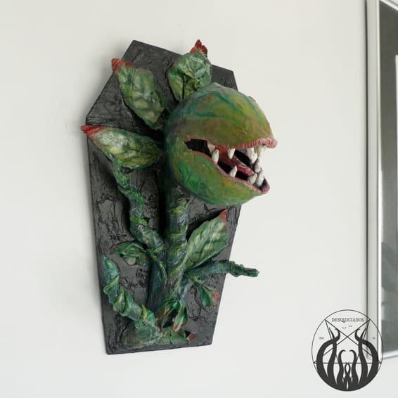 Figura de pared de una planta carnívora verde saliendo de un ataúd