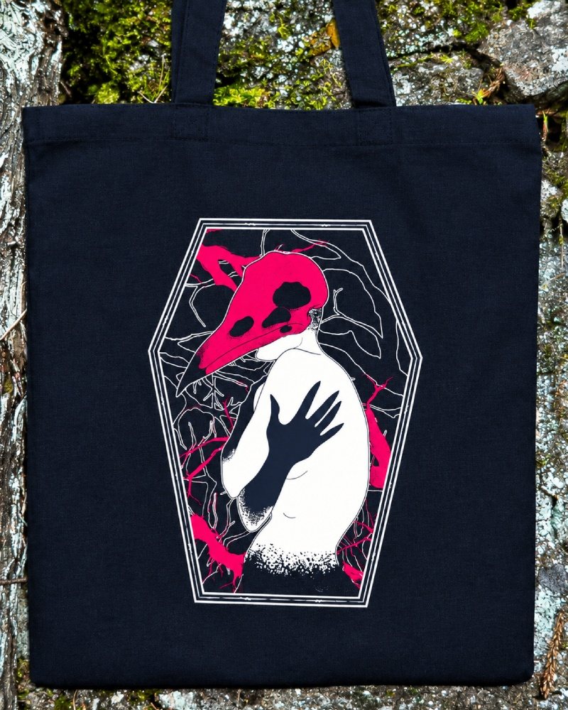 Bolsa de algodón negra con una figura de espaldas y un cráneo de ave rosa dentro de un ataúd
